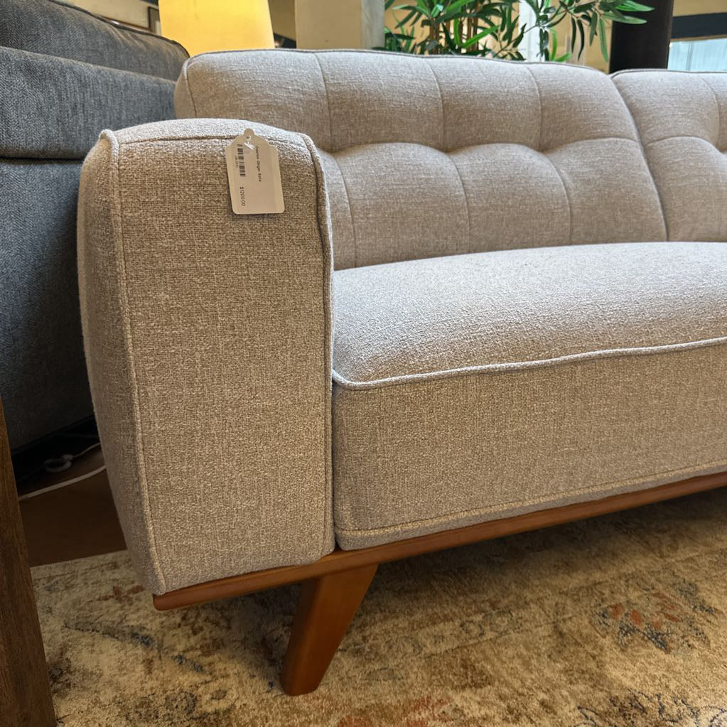 Beige sofa with wooden legs in a room setting