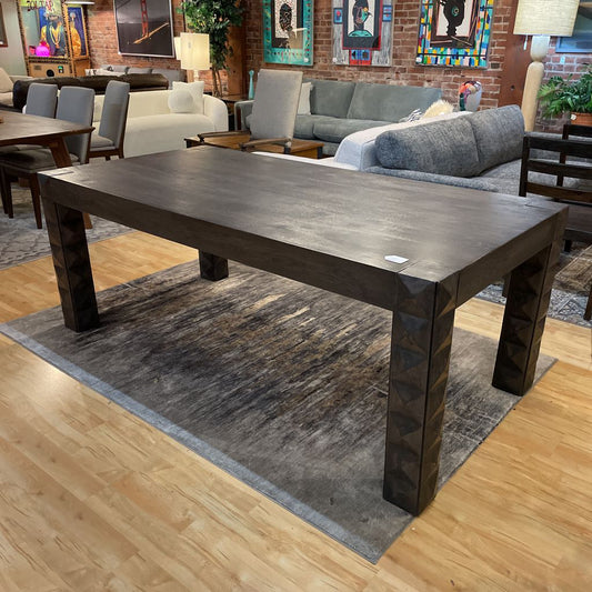 Large dark wooden dining table in a living room setting with furniture and decor.