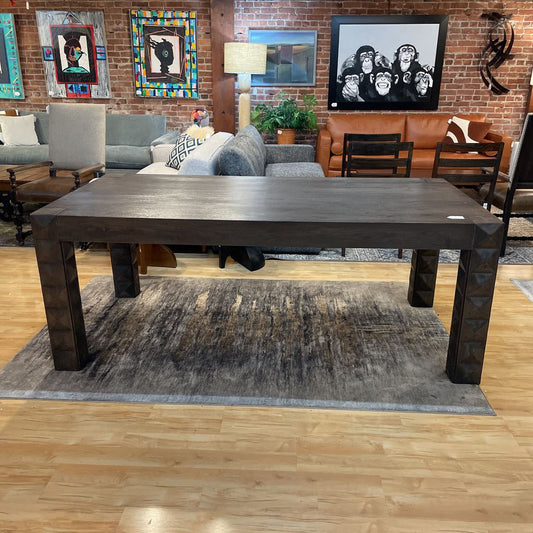 Large dark wooden table in a room with furniture and artwork on the walls.