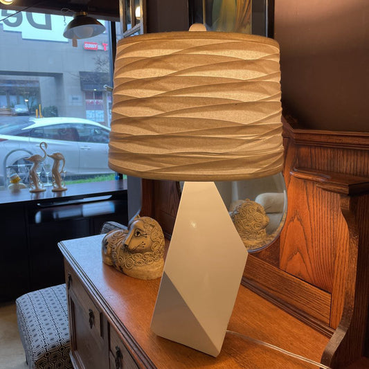 Lamp with a textured beige shade on a wooden surface