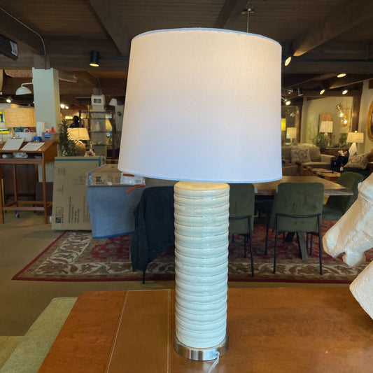 Table lamp with a ribbed cylindrical base and white shade in a store setting