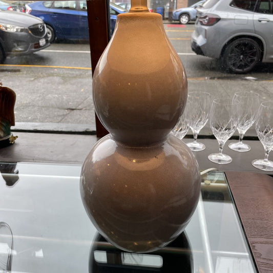 Brown ceramic vase on a table with cars and a street visible through a window.