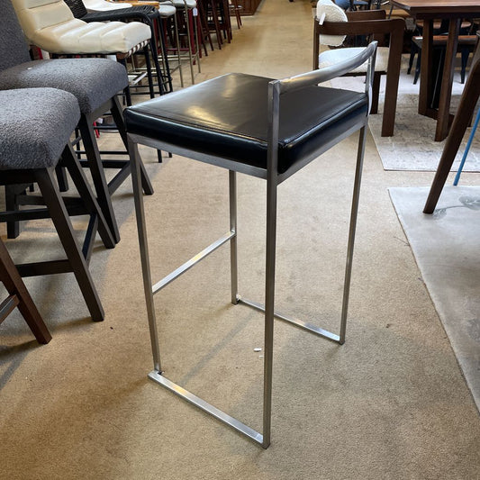 Bar stool with black seat and metal frame on a carpeted floor