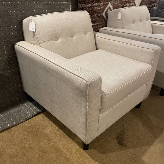 Beige armchair with tufted backrest in a showroom setting