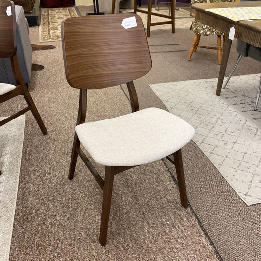Wooden chair with a white cushion on a carpeted floor in a furniture store.