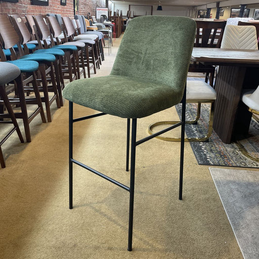 Green bar stool with black legs in a room with other chairs and tables.
