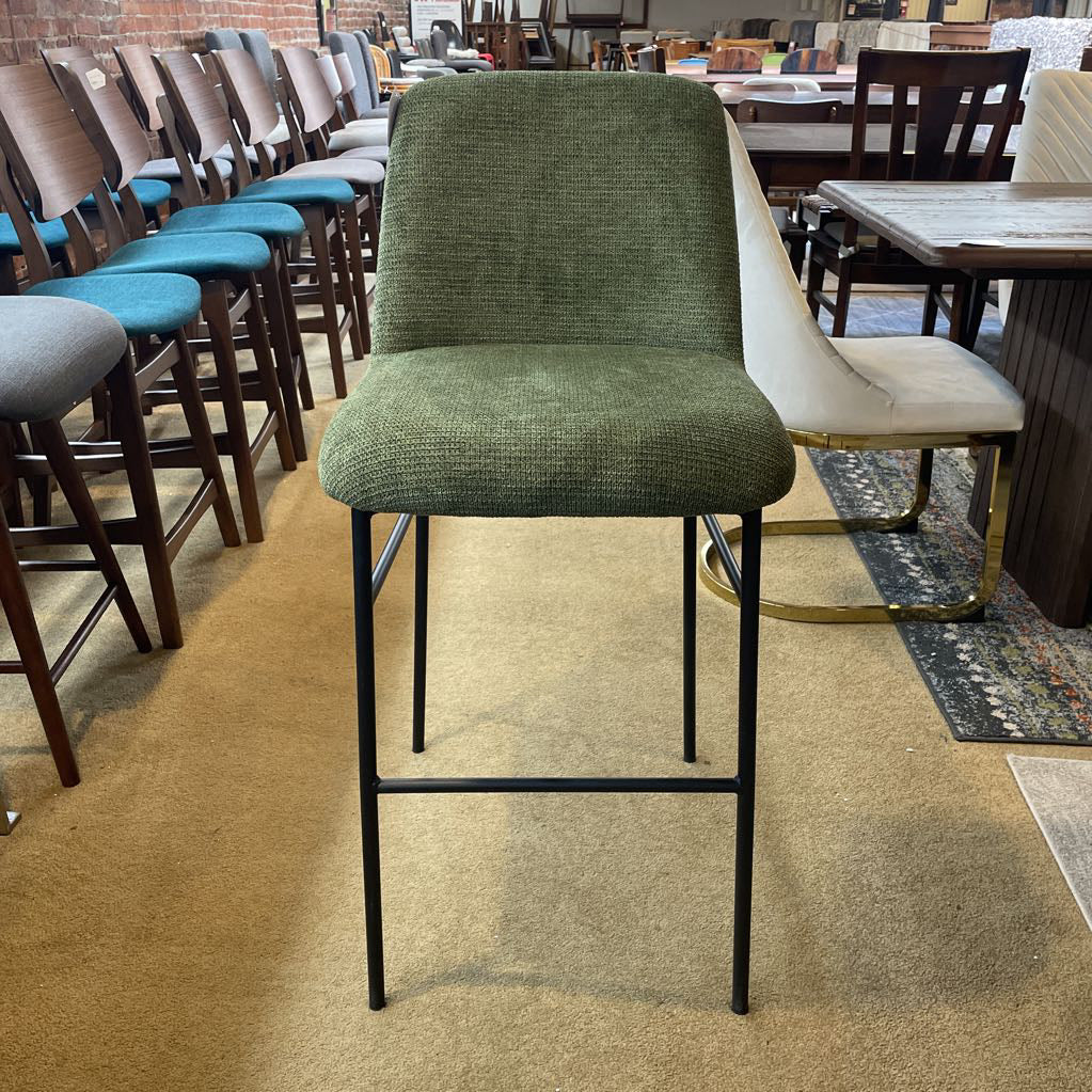 Green bar stool with black legs in a room with other chairs and tables.