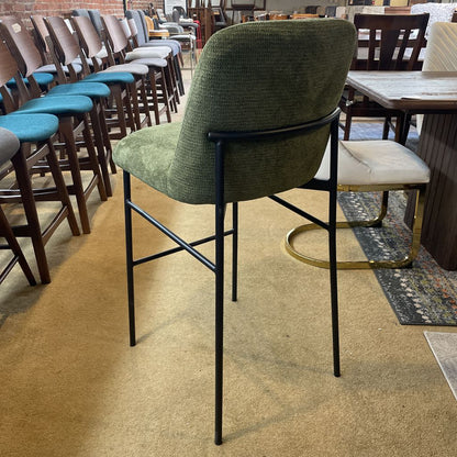Green bar stool with black legs in a room with tables and chairs.