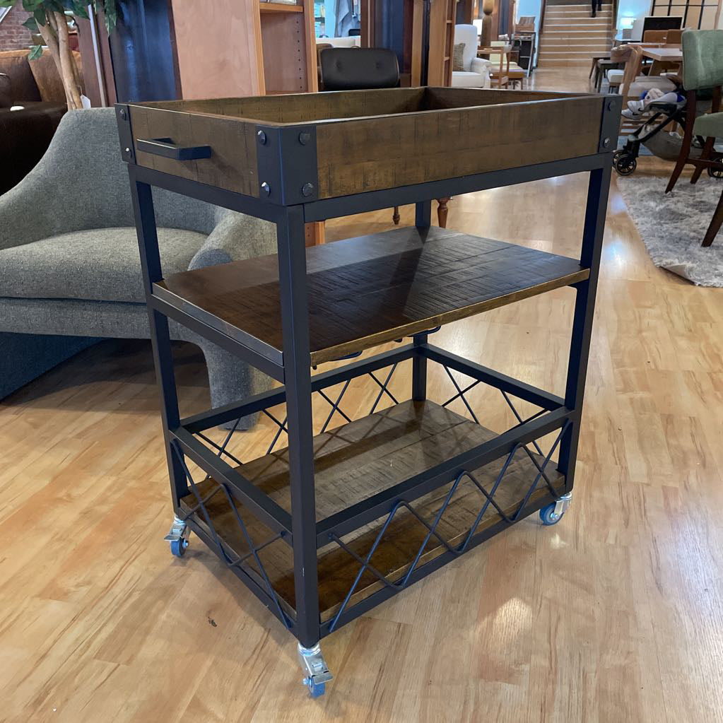 Metal serving cart with wooden top on a wooden floor