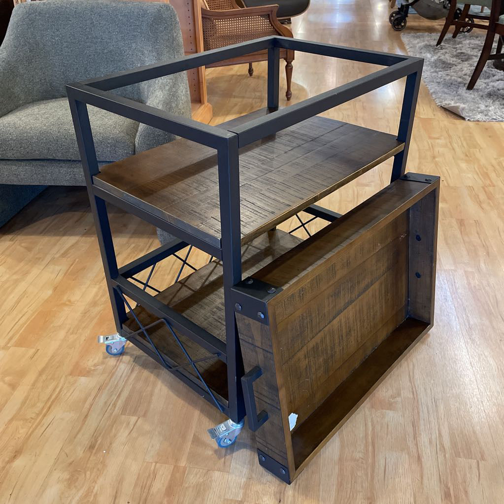 Metal and wood shelf unit on wheels in a room with furniture.