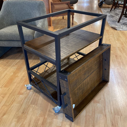 Metal and wood shelf unit on wheels in a room with furniture.