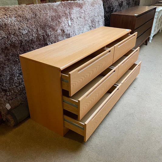Wooden dresser with multiple drawers on a carpeted floor.