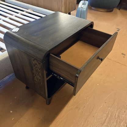 Wooden nightstand with open drawer on a wooden floor