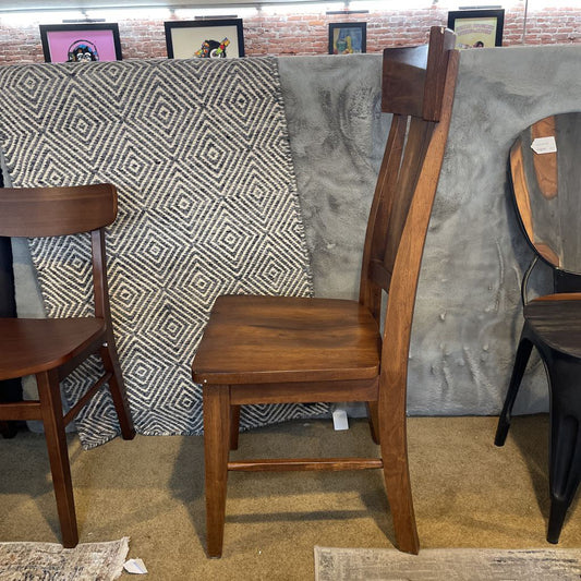 Wooden chair with a patterned fabric draped over it against a brick wall.