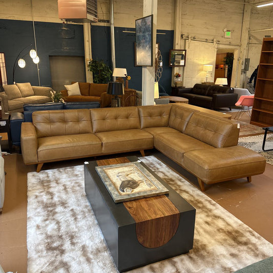 Brown leather sectional sofa with a coffee table in a showroom setting.