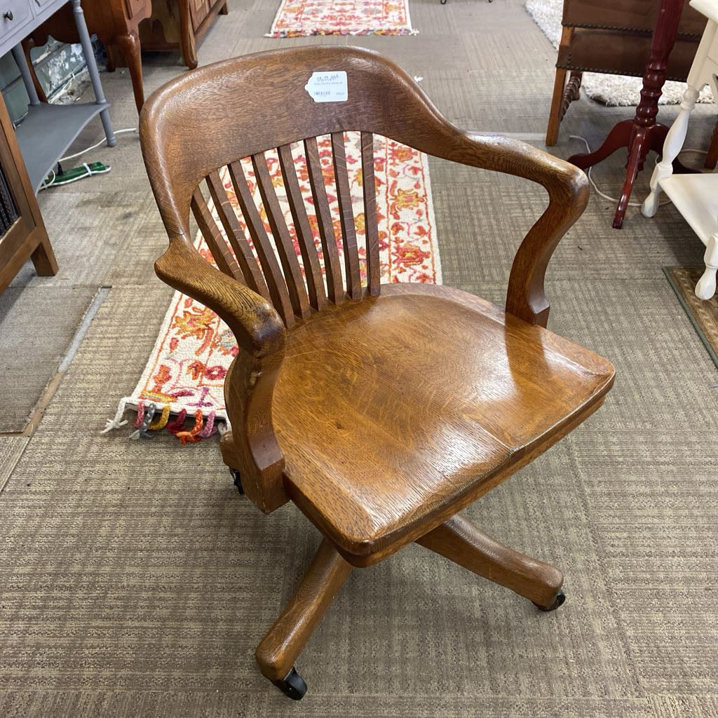 Wooden office chair on a carpeted floor with a rug and furniture in the background
