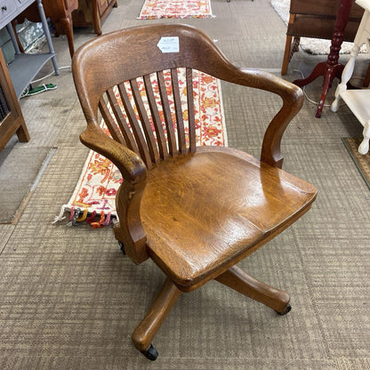 Wooden office chair on a carpeted floor with a rug and furniture in the background