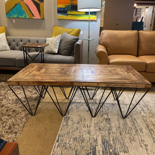 Wooden coffee table with metal legs in a living room setting.