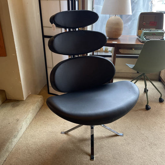 Modern black chair in a room with a desk and lamp.