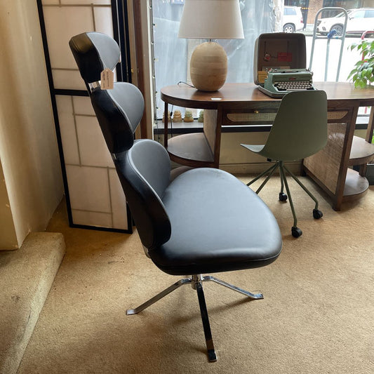 Modern office chair with black seat and gray backrest in a room with a desk and lamp.