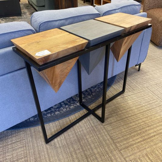 Side table with wooden and gray top next to a blue sofa