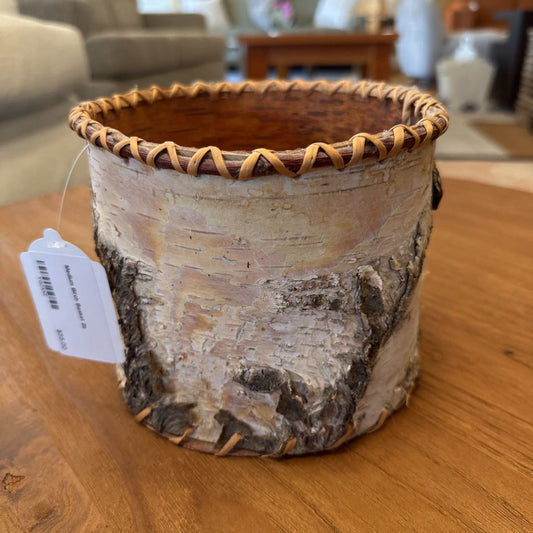 Birch bark pot with woven rim on a wooden surface