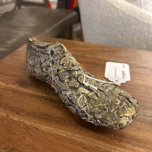Decorative shoe sculpture on a wooden surface with a price tag attached.