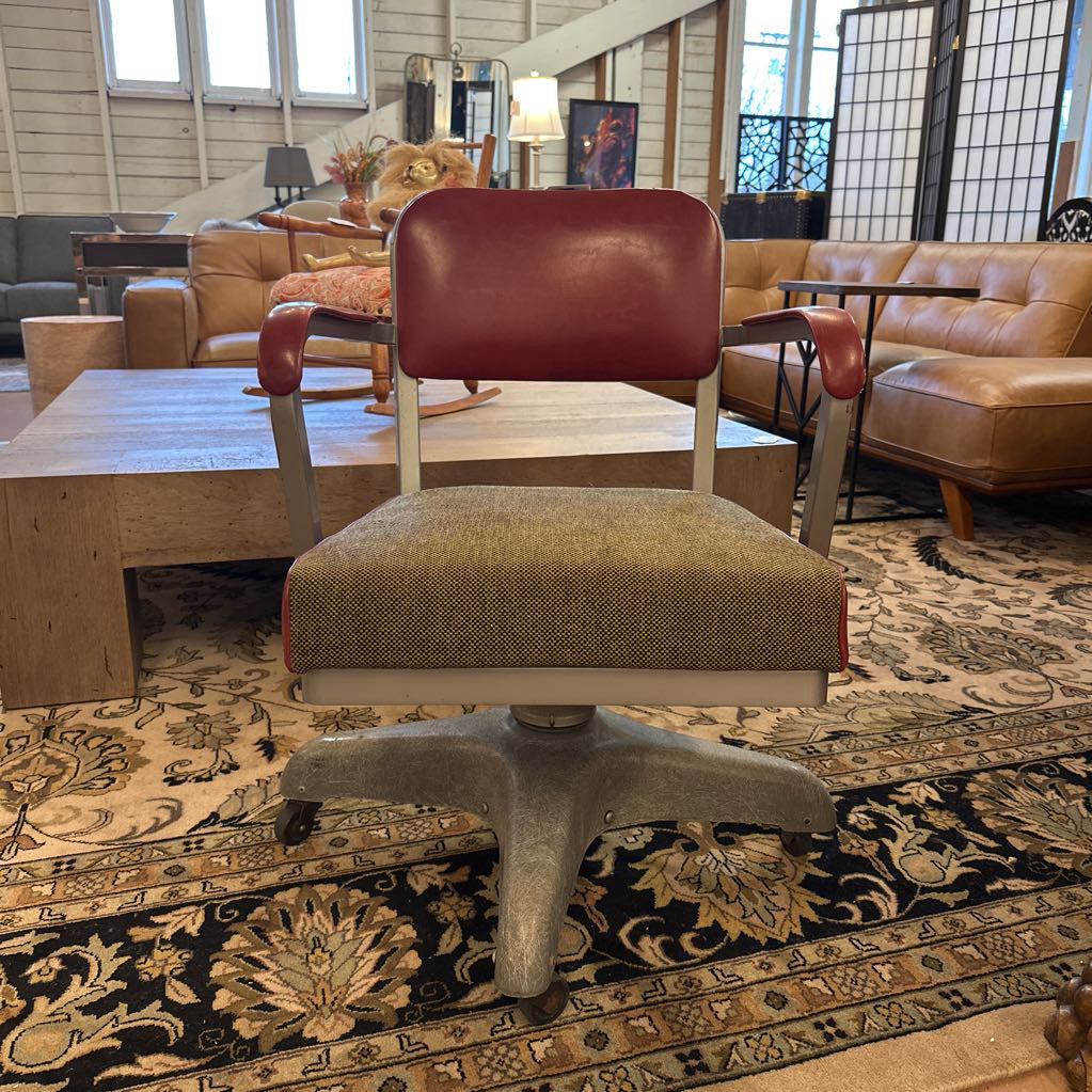 Vintage-style chair with brown cushioned seat and red backrest on a patterned rug.