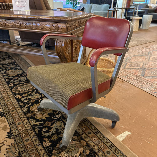 Vintage office chair with red backrest and beige seat on a patterned rug.