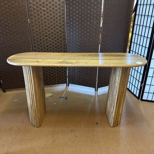 Wooden console table with a textured wall and floor in the background