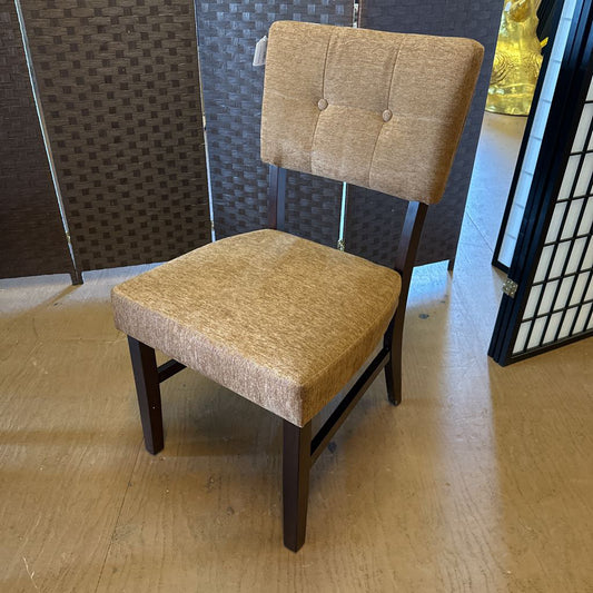 Beige upholstered chair with wooden legs on a wooden floor.