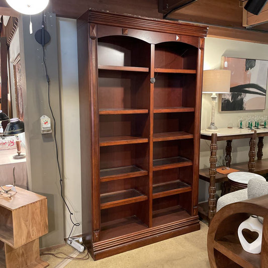 Wooden bookshelf in a room with furniture and decor.