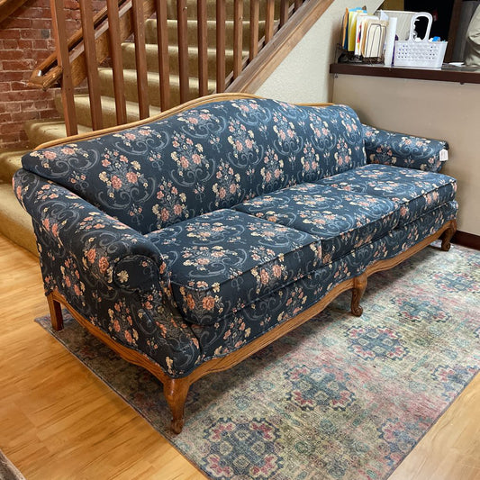 Floral-patterned sofa in a room with wooden staircase and rug.