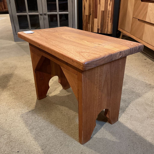 Wooden stool on a checkered floor with blurred furniture in the background