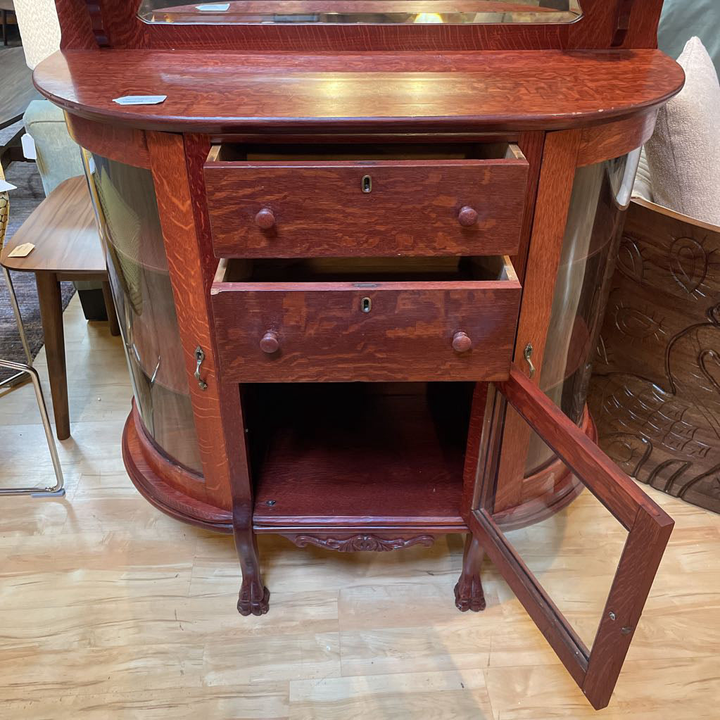Wooden sideboard with glass panels and drawers on a wooden floor.