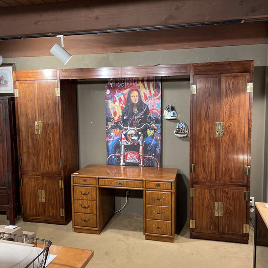 Wooden desk with two large wooden cabinets in a room setting.