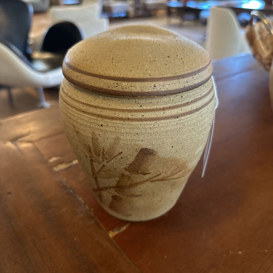 Ceramic jar with lid on a wooden table in an indoor setting