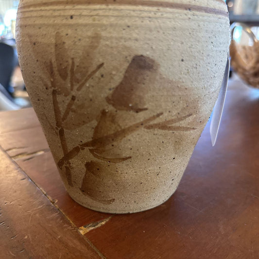 Stoneware vase with floral design on a wooden surface