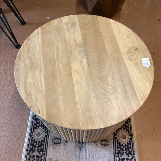 Round wooden table on a carpeted floor with a radiator underneath