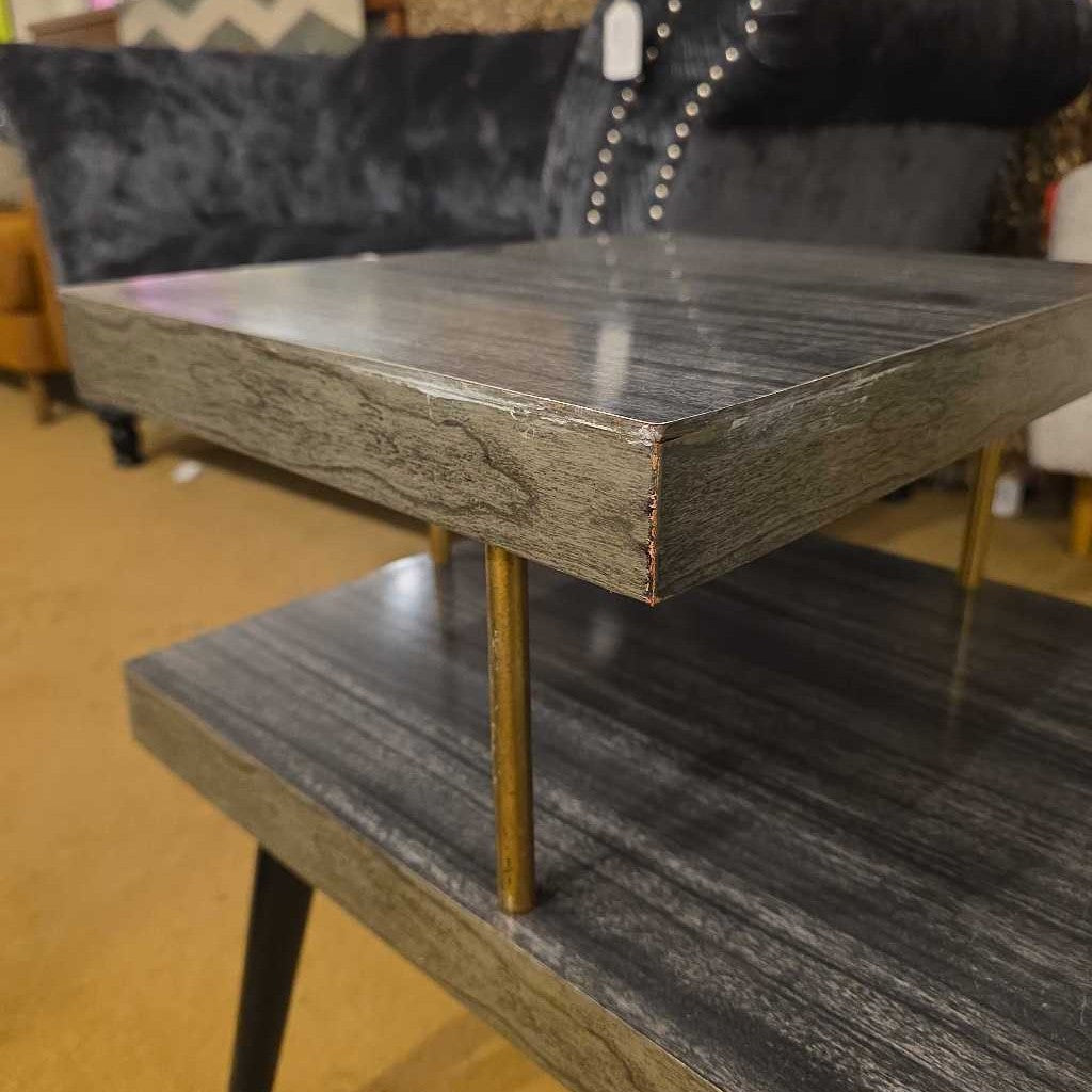 Two-tiered wooden table with a marble-like finish in an indoor setting