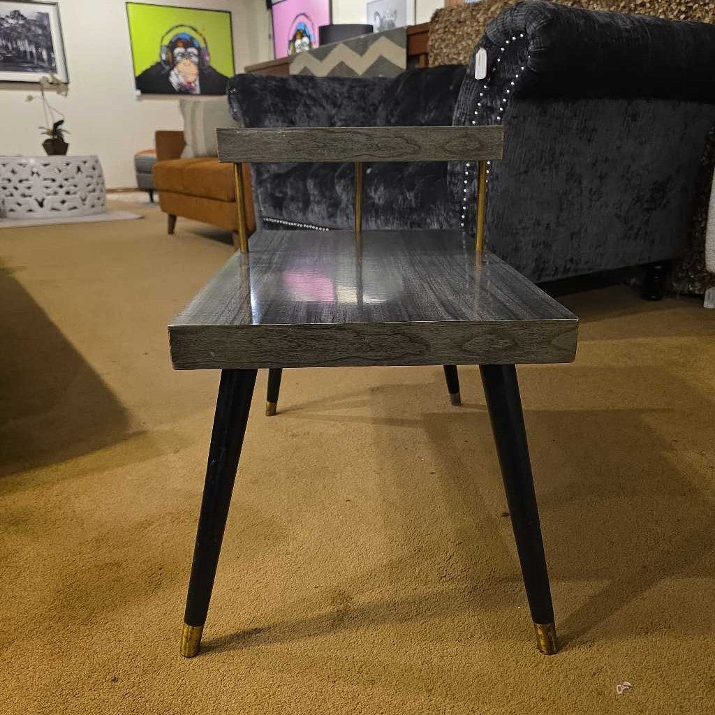 Wooden side table with gold accents in a room with furniture and decor.