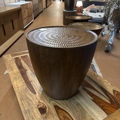 Wooden side table with textured surface on a carpeted floor
