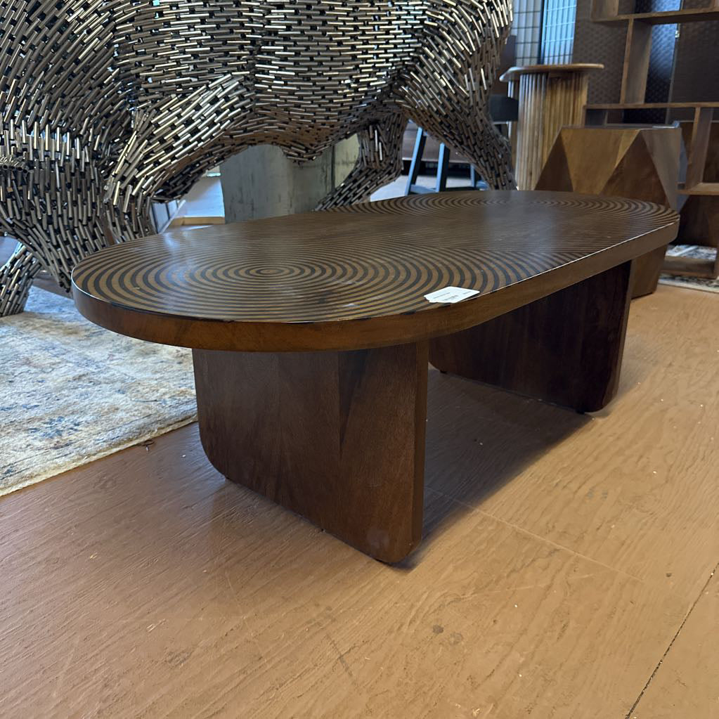 Wooden table with a wavy surface design on a wooden floor.