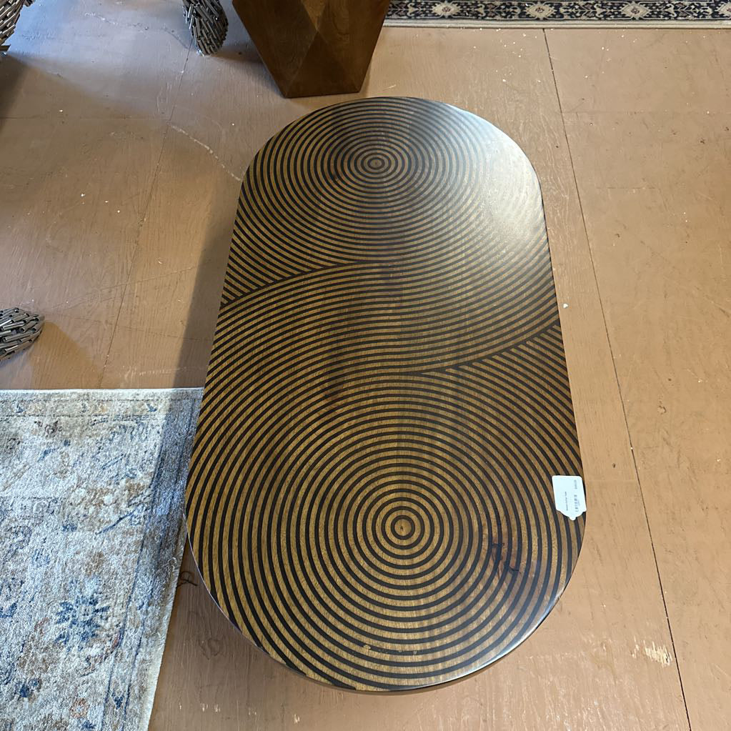 Round metal table with concentric circle pattern on a wooden floor