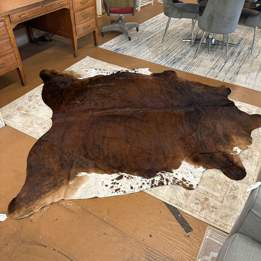 Cowhide rug on a wooden floor with office furniture in the background