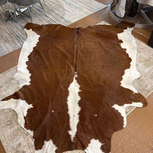 Brown and white cowhide rug on a wooden floor