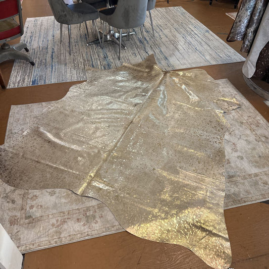 Gold metallic paper on a cardboard surface with a patterned rug in the background