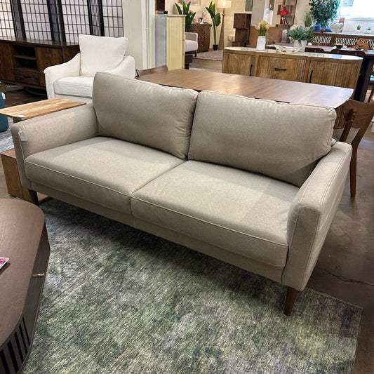 Beige sofa in a room with a rug and furniture