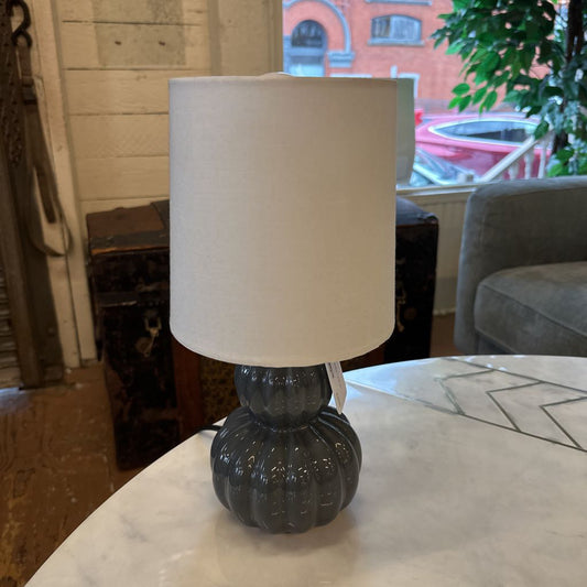 Table lamp with a white shade on a marble surface in a room setting.