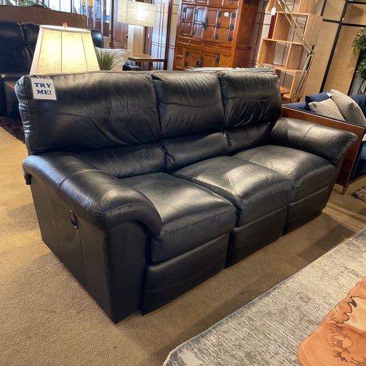 Black leather recliner sofa in a room with furniture and decor.